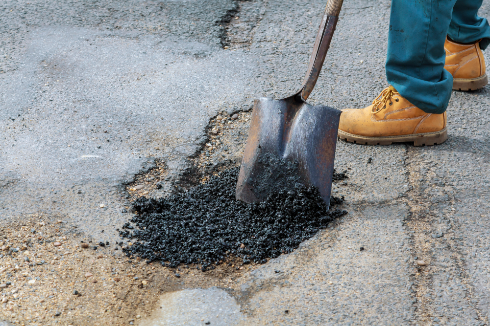 Worker filling a pothole with repair material