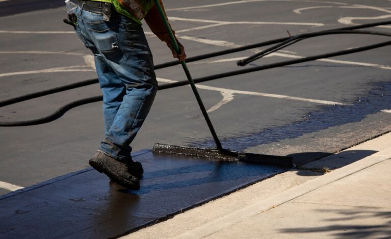 Worker,Using,A,Sealcoating,Brush,During,Asphalt,Resurfacing,Project