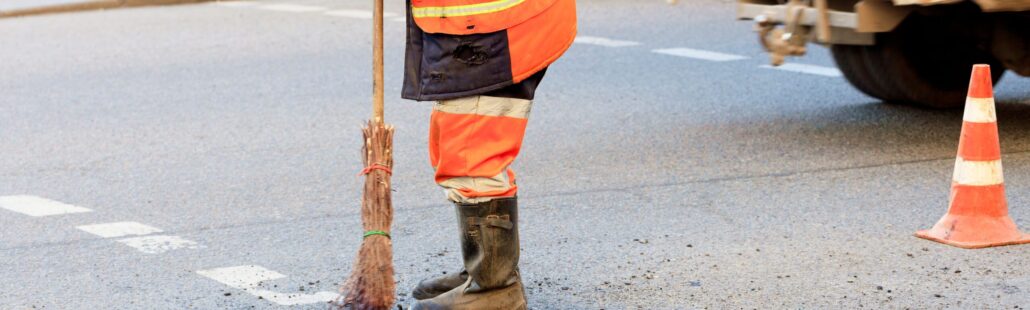 A road worker levels a fresh asphalt by a wooden level on a repaired road section in road construction