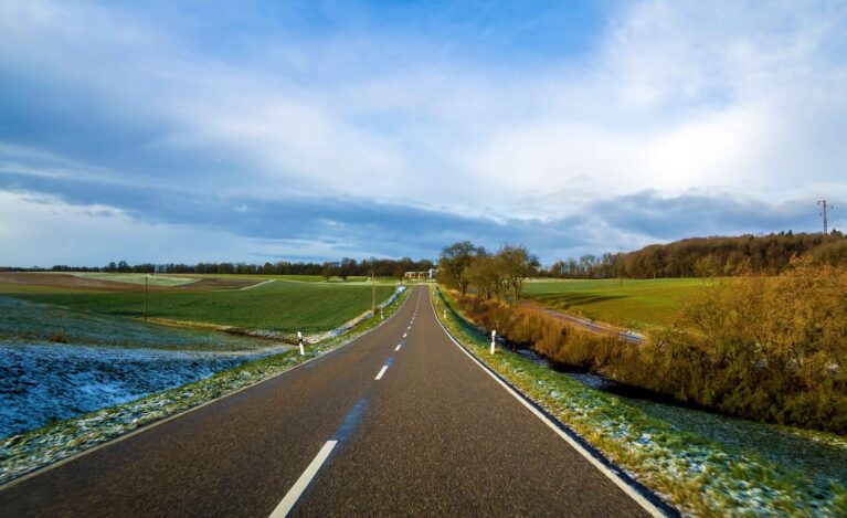 empty-black-asphalt-road-between-green-fields-2025-06-29-06-45-17-utc_11zon