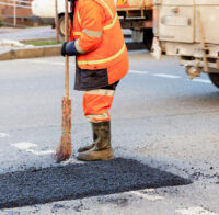 road-worker-levels-a-fresh-asphalt-by-a-wooden-lev-2025-02-08-22-08-29-utc-(1)