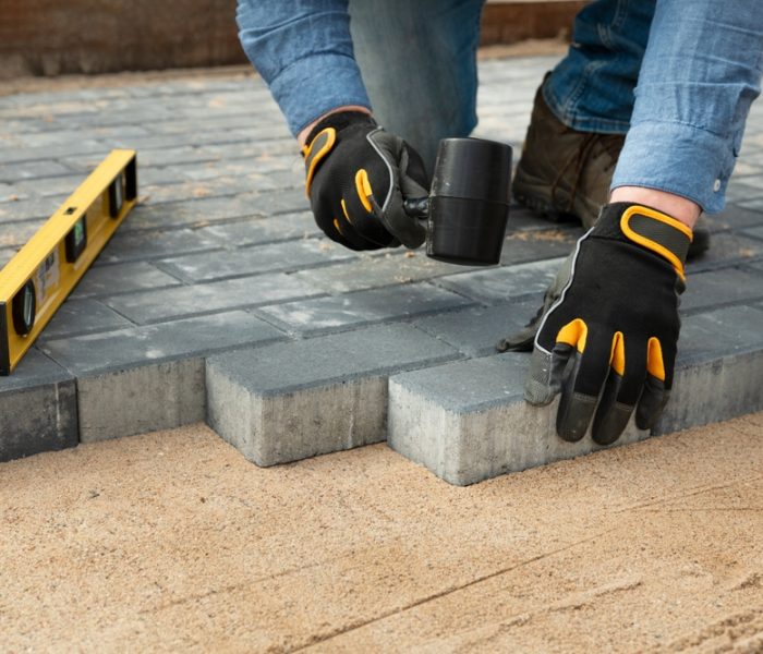 Construction,Worker,Laying,Cement,Pavement,On,A,Walkway,With,Gloves